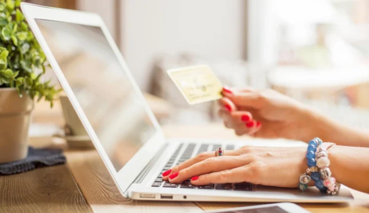 Best practices for hoteliers using gift card solutions - A person with red nails types in their card information into a laptop - Sabre Hospitality