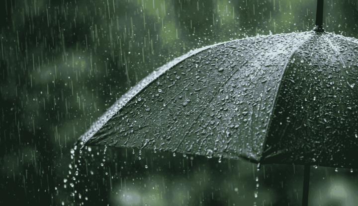 Booking with confidence: How weather protection enhances guest satisfaction - rain drops falling on an umbrella with a green background - Hospitality Solutions
