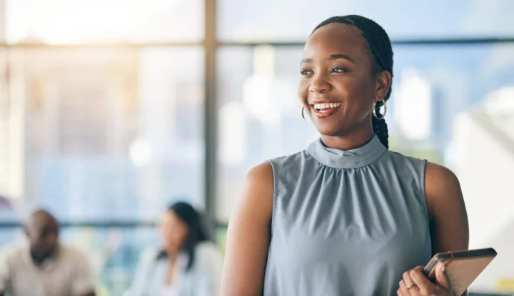 Why hospitality solutions are essential for modern hoteliers - A woman smiles while holding a tablet in a hotel lobby - Sabre Hospitality